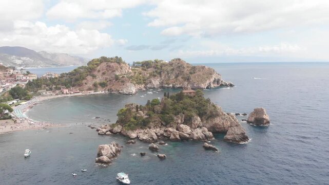 Aerial drone circular shot orbiting around Isola Bella off the coast of Taormina, Sicily, with the Mediterranean Sea surrounding the island.