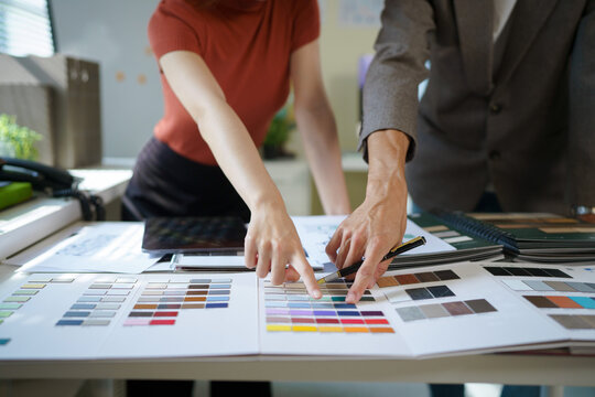 Two designers collaborating over color swatches and material samples on a studio desk, ideal for interior design, branding, and creative agency concepts