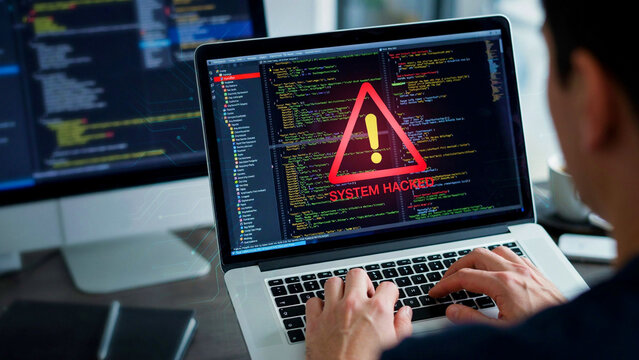 Male programmer typing code with cyber attack warning overlay on screen during late night work session