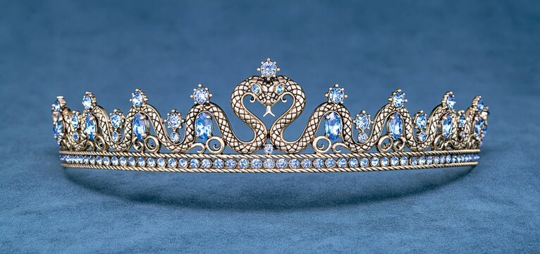 A detailed gold serpent crown adorned with blue gems resting on rich velvet fabric, perfect for cultural and heritage displays.