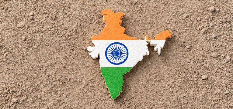 Against dry, rugged soil, an outline of India filled with the tricolor symbolizes resilience and unity for national celebrations.