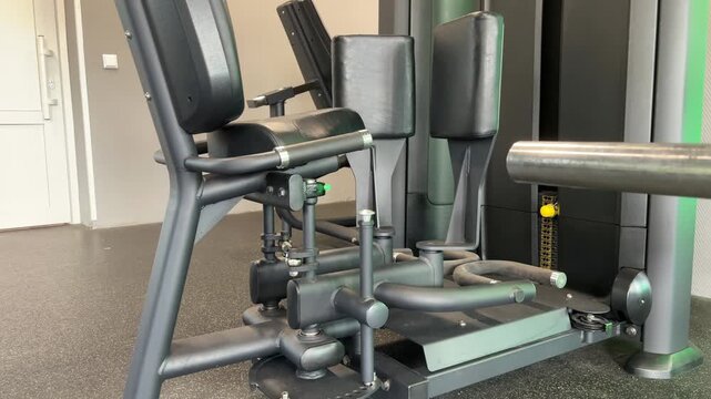 An unoccupied hip exercise machine has padded leg supports and a weight stack in a gym, resistance equipment, fitness facilities, workout preparation.