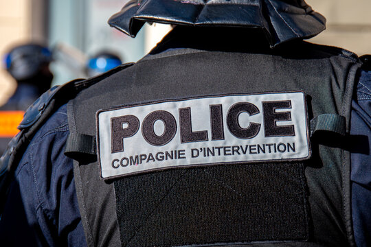 Gros plan d'un marquage "POLICE - Compagnie d'intervention" &eacute;crit &agrave; l'arri&egrave;re du gilet tactique d'un officier de police fran&ccedil;ais pendant une manifestation &agrave; Paris, France