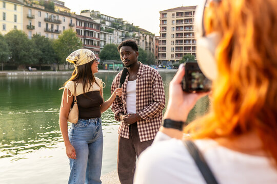 Diverse friends interviewing by canal in milan city