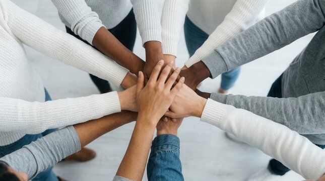 A multicultural group of business professionals stacking hands in a gesture of teamwork.
