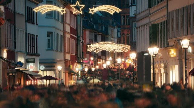 Loads of people with motion blur rushing and shopping on the historic German city of Heidelberg at Christmas. With holiday decoration shining lamp posts.