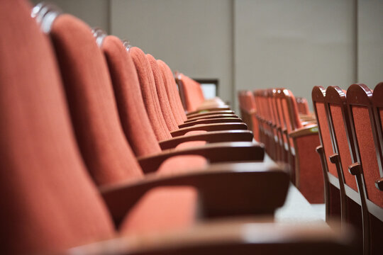 Empty theater seats with red upholstery in rows focused from side angle