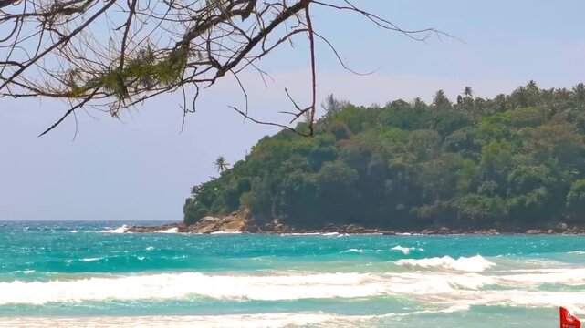 Tropical Ko Pu Island beach turquoise waves sand jungle palms blue sky Kata Beach Phuket Thailand.