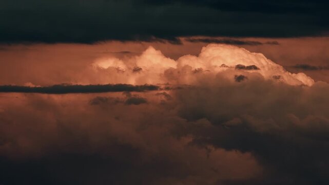 Dramatic cumulus clouds moving in the red sky. Weather time lapse with moody sunset light. 