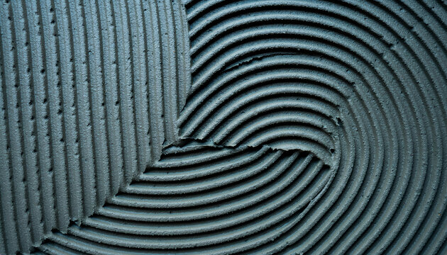 Abstract textured cement adhesive with parallel and swirling trowel patterns.