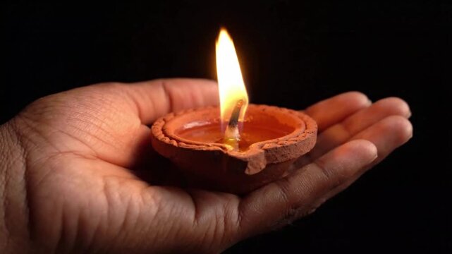 Close Up of Hand Holding Lit Clay Diya Lamp for Diwali Celebration