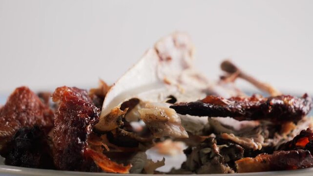 Food waste with leftover chicken bones on a plate. Kitchen leftovers and household food waste concept. High quality 4k footage