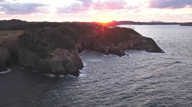ドローン空撮による夕日と七ツ釜の断崖絶壁 4K映像素材 マジックアワーの夕焼け空と海食洞の美しい海岸線自然風景