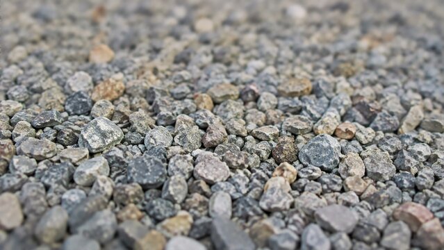 Texture of gravel driveway stones with selective focus. Close-up surface of small gray pebbles and crushed rock for landscaping and construction