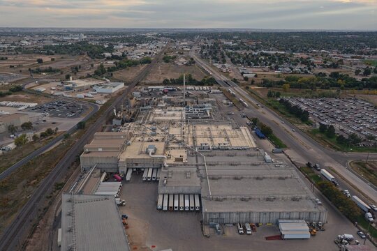 Aerial view of a large industrial facility with multiple loading docks, parked semi-trucks, and surrounding infrastructure in Greeley, Colorado, United States.