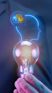 Hand holding glowing lightbulb vertical shot with head profile and cognitive feedback bubble icon. Creative thinking brainstorm process, mental iteration agility, and corporate intellect concept.