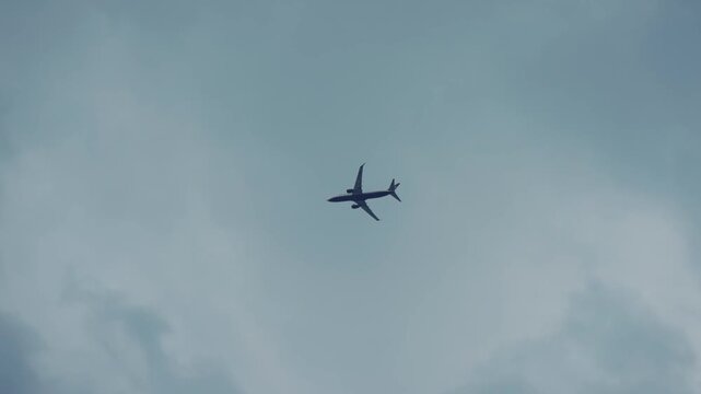 A large jet is flying landing at night. The sky is dark and the clouds are thick, giving the scene a moody and ominous feel