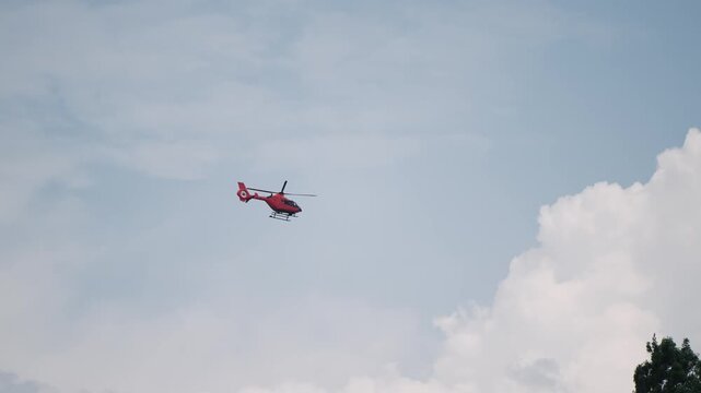 A red first aid rescue medical helicopter is flying in the sky