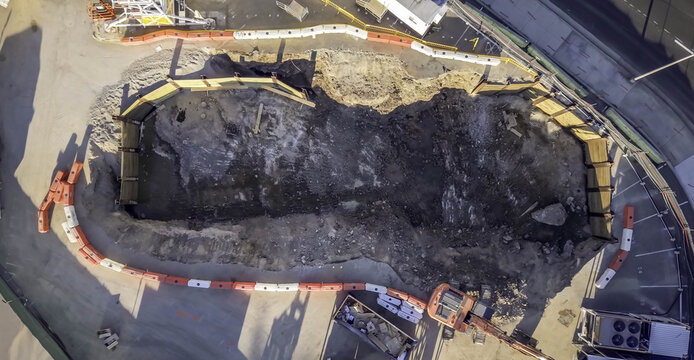 Aerial view of the Boring Company tunnel construction site featuring a deep excavation pit, orange and white safety barriers, and heavy machinery in Nashville, TN, United States.
