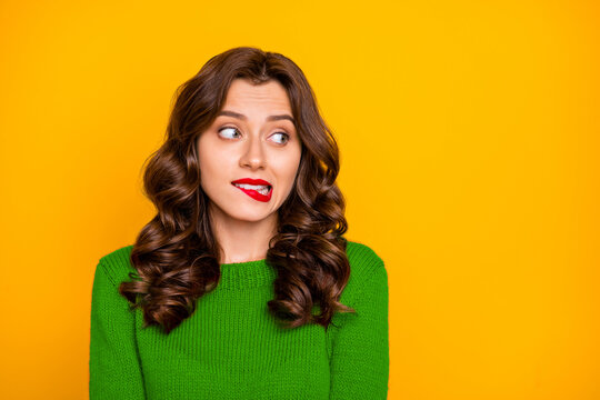 Photo of charming stylish curly wavy trendy cute attractive nice sweet pretty girlfriend biting her lips while watching something away isolated over yellow vibrant color background