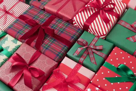 Red and green Christmas presents arranged as a decorative background. Festive wrapped Christmas gift boxes with ribbons, bows  and holiday patterns.	
