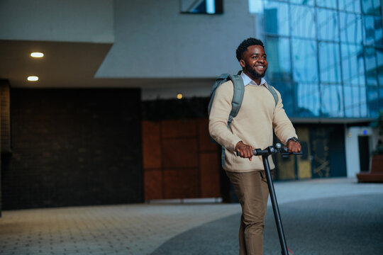 Young black man commuting on electric scooter in city