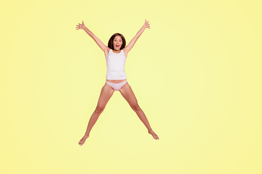 Good morning! Full length size body young gorgeous nice straight-haired lady wearing sleepwear, jumping in air, making star figure. Isolated over pink pastel background