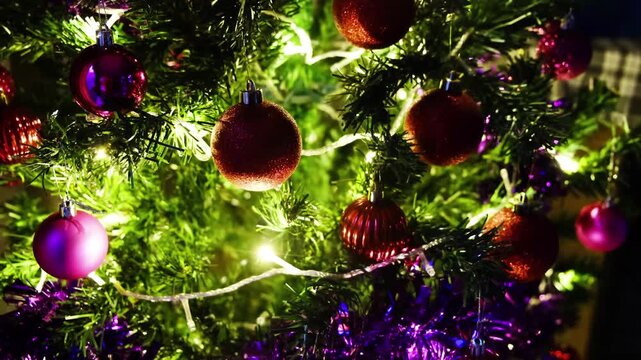 A Christmas tree adorned with various decorative baubles in shades of red, pink, and gold. 