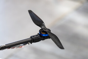 Carbon fiber drone propeller mounted on brushless electric motor arm. Close view displays composite rotor blade on unmanned aerial vehicle frame. © Mati