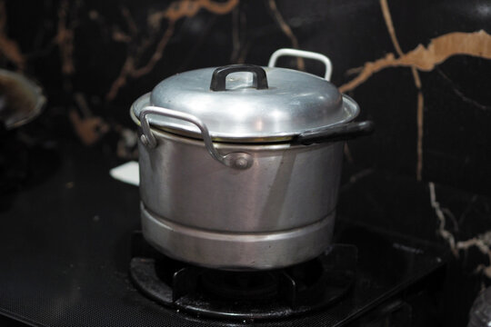 closed metallic stock pot with a lid sits on a black stove top in a home kitchen setting