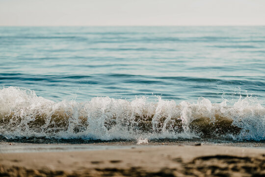 Ocean wave breaking on sandy beach under clear sky in a beach