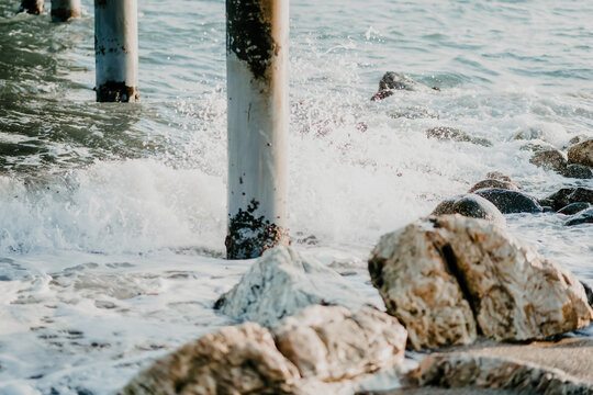 Waves crashing on rocks and pier pillars at the spanish seashore