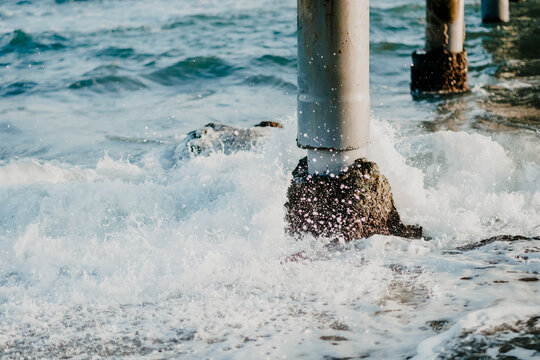 Waves crashing on pier pillars in ocean water at coastal Spain