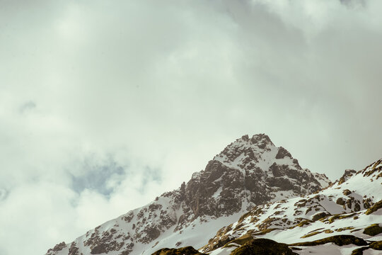 Snow-covered rocky mountain peak in Spain with overcast sky