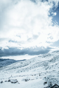 Snow-covered mountain slope under partly cloudy sky