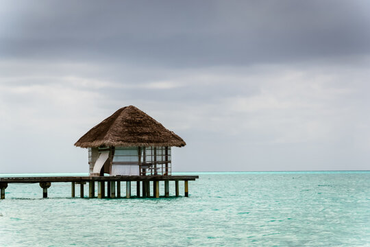 Overwater bungalow on a wooden pier over turquoise ocean