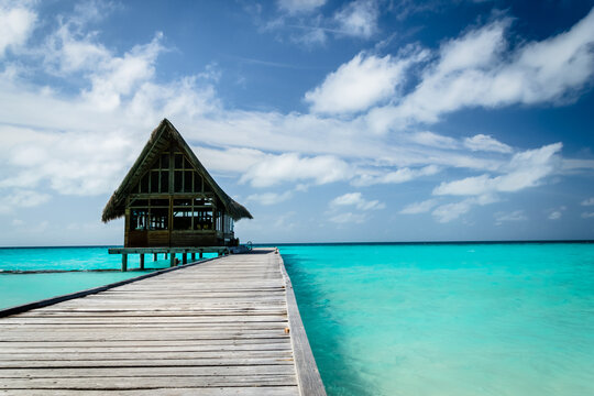 Wooden pier with thatched hut over turquoise water
