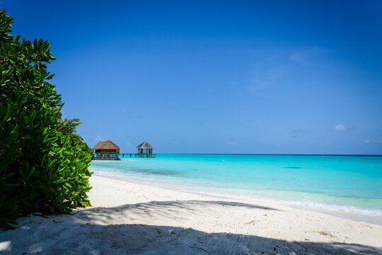 Beach with turquoise water and overwater huts in a beach