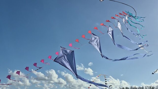 Large traditional kites flying above visitors during a colorful beach festival