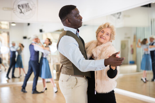 Elderly woman learning ballroom dancing in pair in dance studio