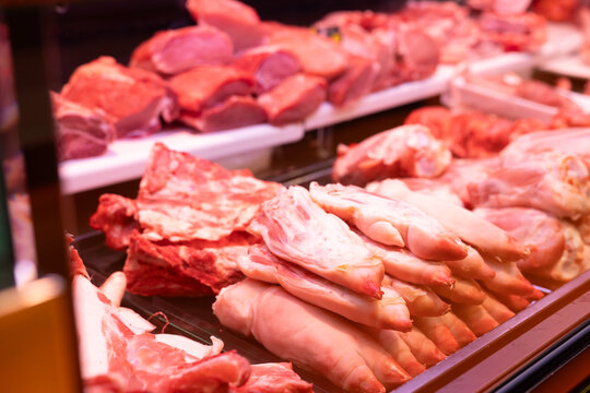 Display case in meat department of supermarket - raw pork legs are stacked