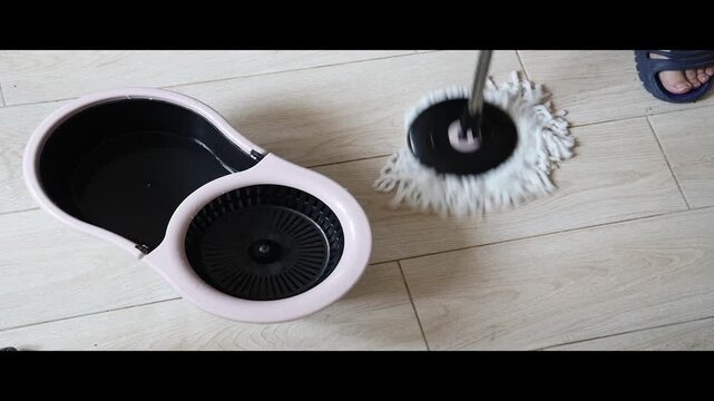 mop is squeezed, wring into bucket, ready to clean floor with tiles background Top view Male Housekeeper cleaning with rotating mop housekeeper cleaning tiled floor using rotating mop with spin-dryer