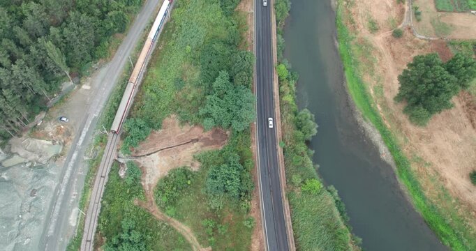 Traffic of train on railway and car vehicles on road, aerial view