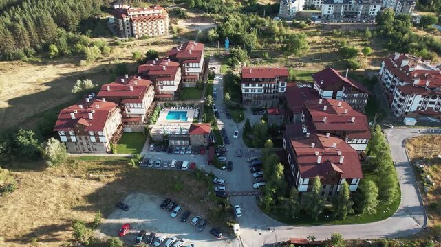 Luxury hotel complex mountain resort in Bansko at sunset, aerial view. A view of a field with trees and a path. The trees are sparse and the grass is dry