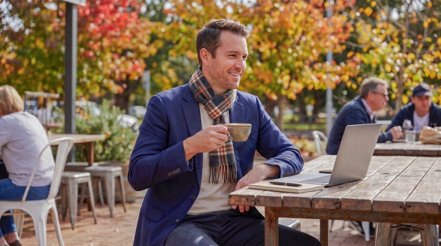 Freelancer man drinking coffee at an outdoor cafe in autumn