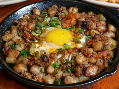 Filipino pork sisig with egg and scallions in skillet