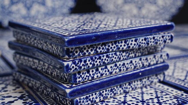 Stack of handmade blue and white ceramic tiles on pottery table. Traditional Mexican Talavera and Portuguese Azulejo craft