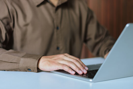 Businessman hands typing on laptop keyboard close up at white office desk