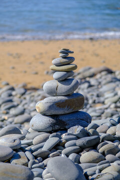 A precarious stack of balanced stones on a Cornwall beach, a metaphor for life's delicate stability and resilience