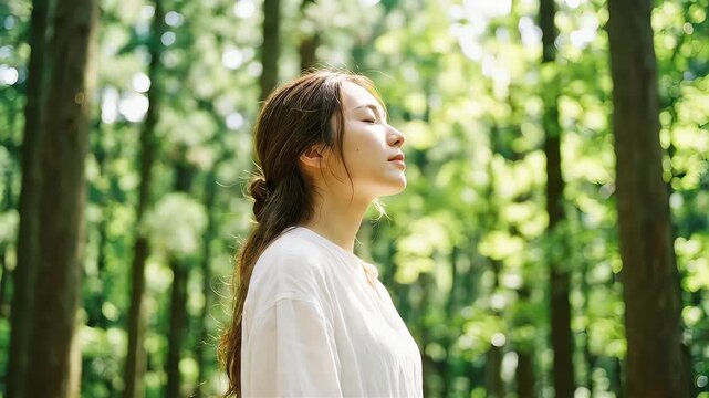 森の中で目を閉じて深呼吸する女性